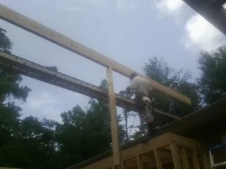 Carpenter setting a ridge beam over a new addition frame — Ice Dam Removal by Roofing Brothers in Griswold