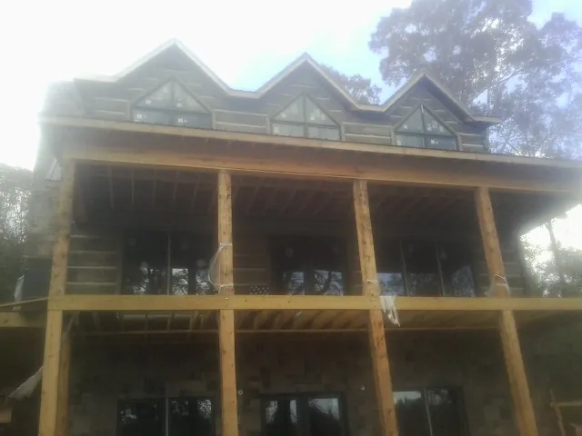 Dormers and porch framing on a large log home under construction — Roof Coating work by our crew in Griswold