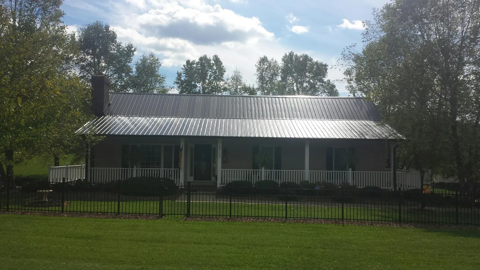 Gray metal roof on a brick ranch with a full width front porch — Gutter Guard Installation work by our crew in Griswold