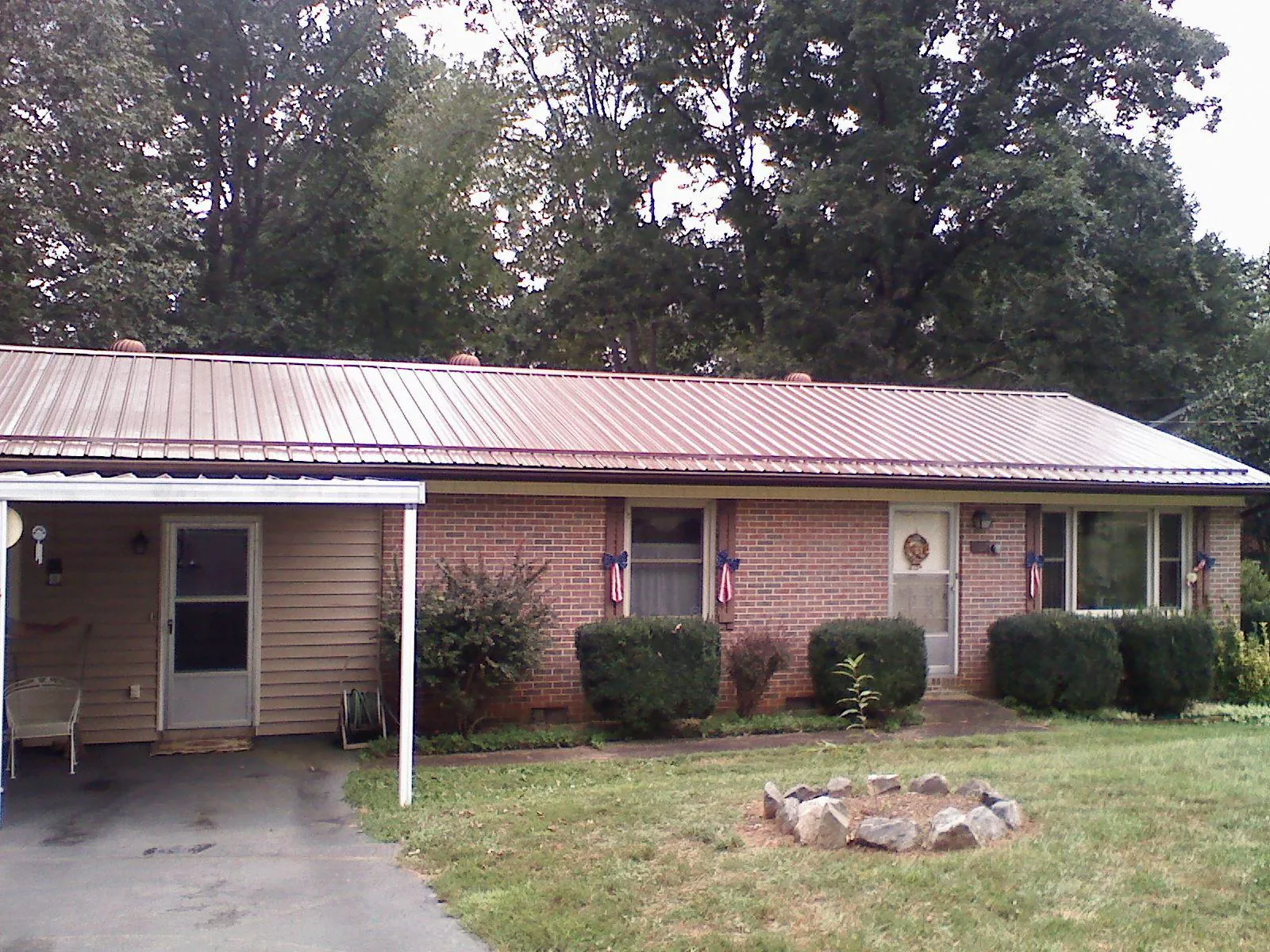 Bronze metal roof and carport on a brick ranch home — Roof Repair work by our crew in Griswold